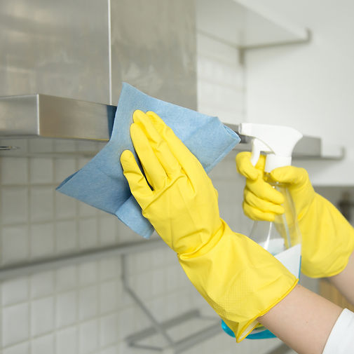 Close up of female hands in rubber protective yellow gloves cleaning the kitchen metal ext