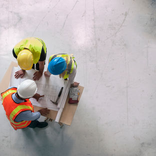 Builder and site manager reviewing construction drawings for a house extension project