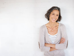 Woman calmly standing in front of a white wall with her arms folded