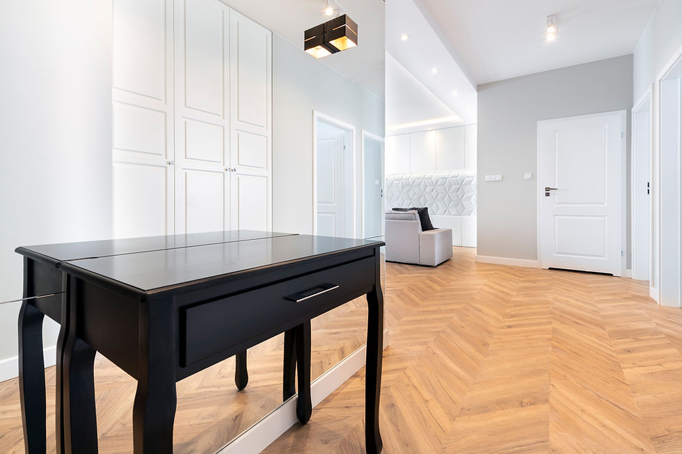 a modern hallway featuring a black console table in the foreground and light wood herringbone flooring