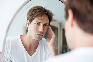 Man looking at self in mirror with concerned look