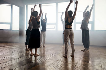 Group of dancer teachers standing in a circle with their arms stretching in the air