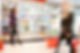 Blurred motion of people walking near refrigerators in shopping centre with baskets