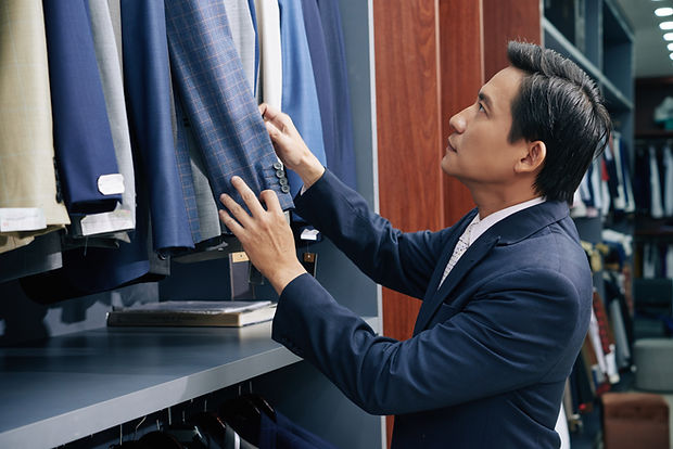 Asian man picking a suit in a menswear shop