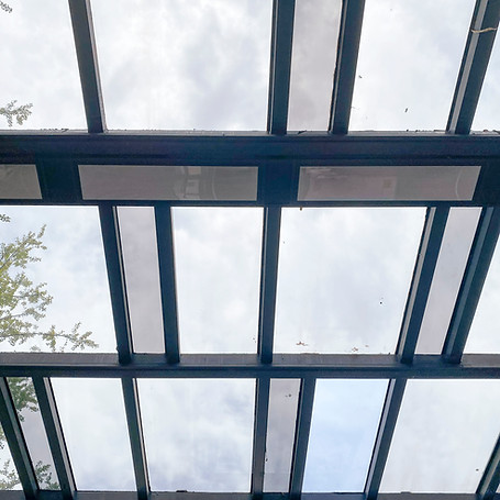 View of the sky through a glass roof with metal beams