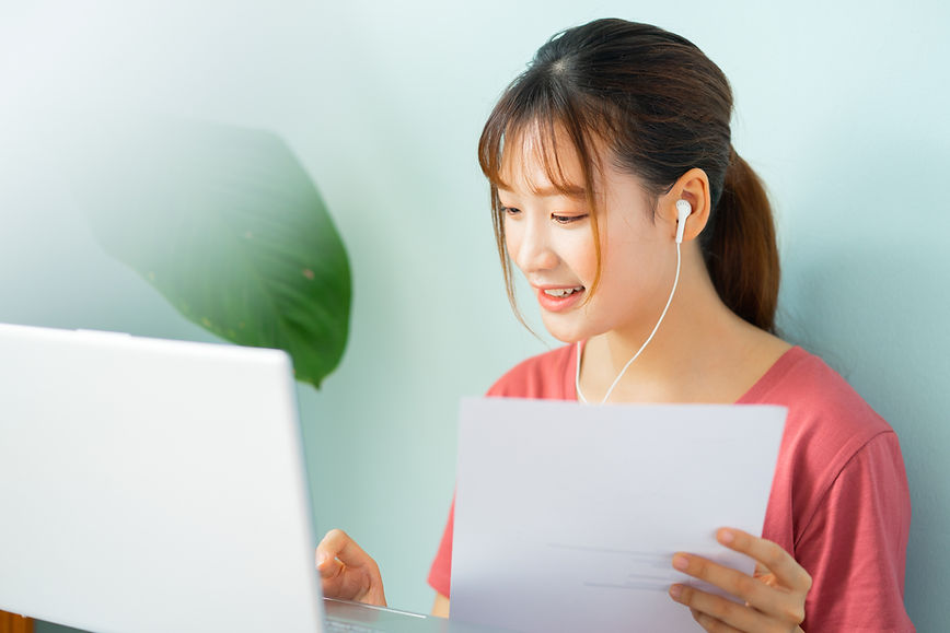 Asian woman wearing earphones while working at home
