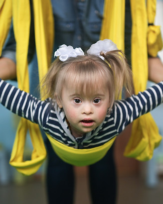 Young child swinging in yellow lycra swing for vestibular and proprioceptive input