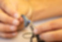 Hand holding a small modern black receiver in canal hearing aid