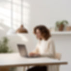 Une femme assise à une table qui travaille devant son ordinateur.