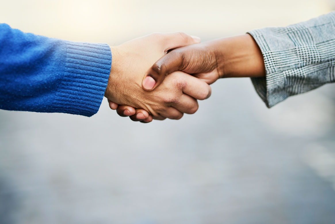 Two individuals shaking hands, one wearing a blue sweater