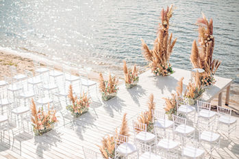 Ceremonia de boda frente al mar con sillas blancas y pampas