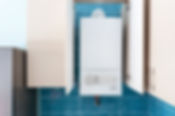 White gas boiler mounted in wall cupboard