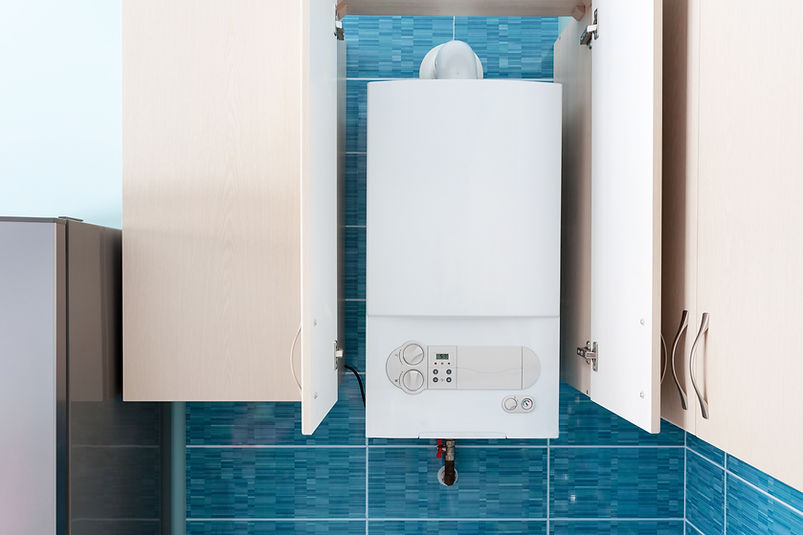 White gas boiler mounted in wall cupboard