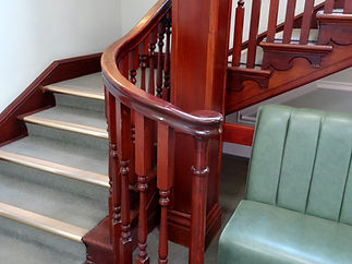 Ornate wooden spindles and curved bannister of a grand staircase in a stately entryway