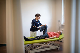 Female physiotherapist treating senior male patient leg at rehabilitation. Physiotherapist