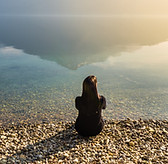 Sitzen an einem See bei Sonnenuntergang