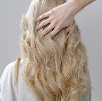 Hand touching long wavy blonde hair from behind