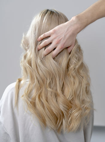 Healthy, wavy blonde hair after a successful hair color transformation from dark to blonde.