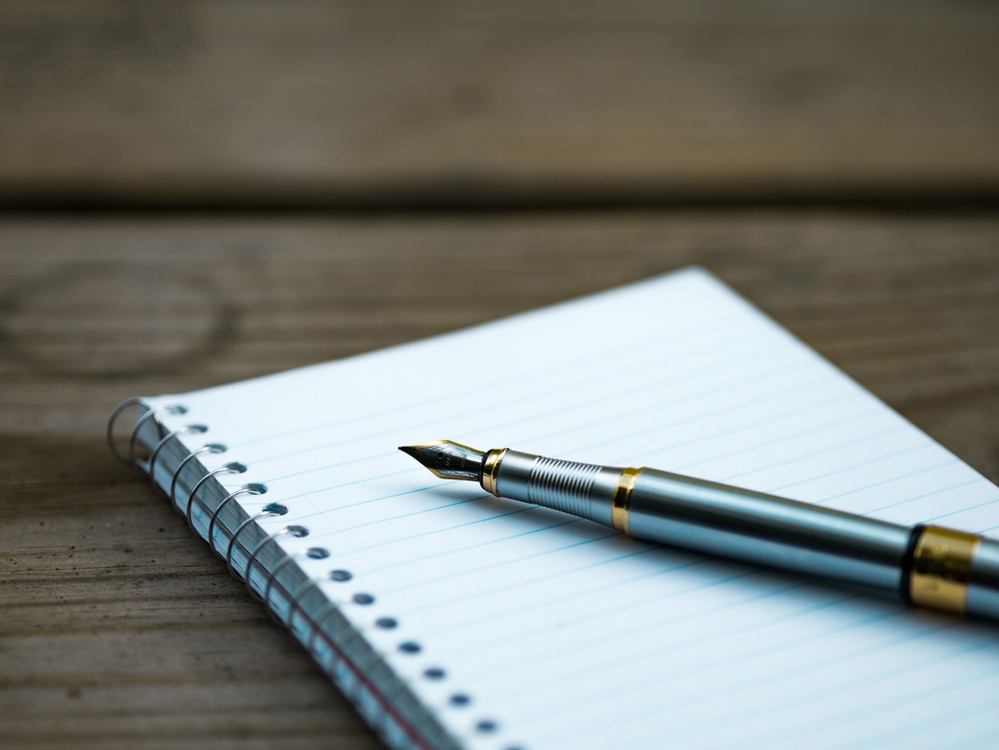 Un stylo plume est posé sur un carnet de notes ouvert.