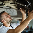 Car repairman using lamp while analyzing auto breaks in a repair shop