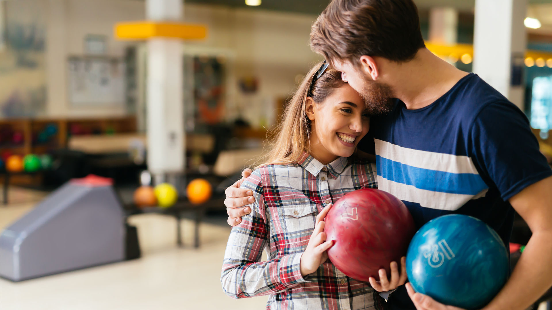 Couple complice au bowling de Bandol, une boule rouge et une boule bleue à la main