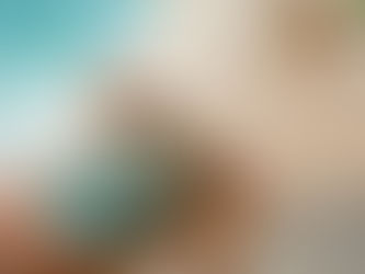 Person in green swimsuit lounges beside a pool, holding a large straw hat covering their face. Relaxed summer vibe, poolside setting.