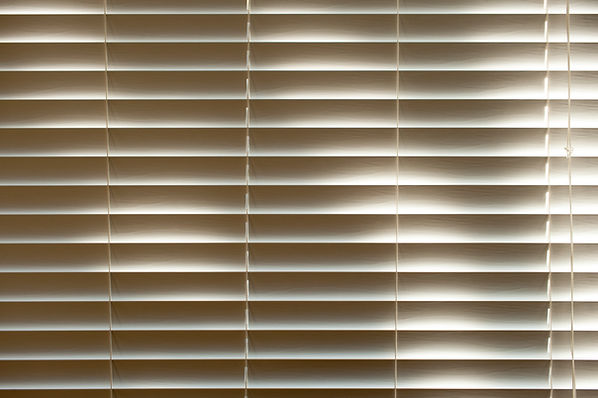 Close-up detail of cream horizontal blind slats showing subtle wood grain texture