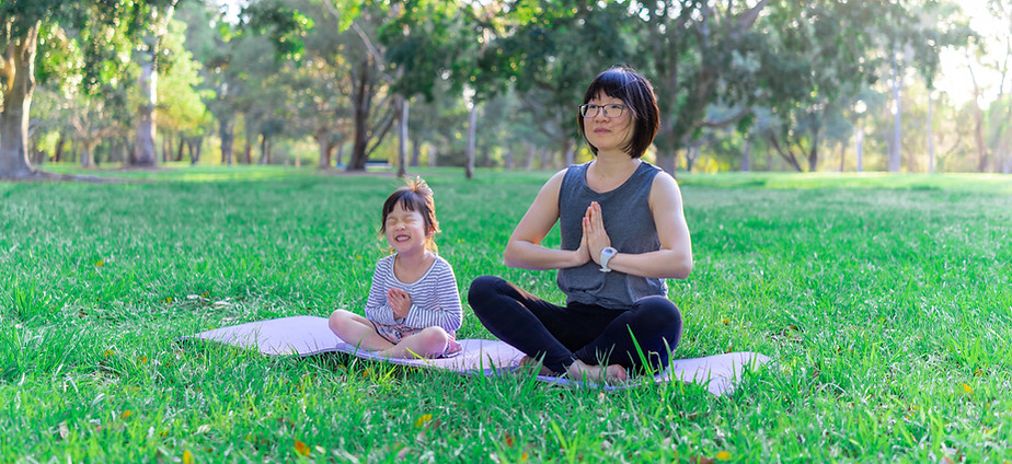 Woman and girl meditating in a park