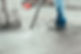 A person in jeans and work boots uses a pressure washer to clean a concrete surface