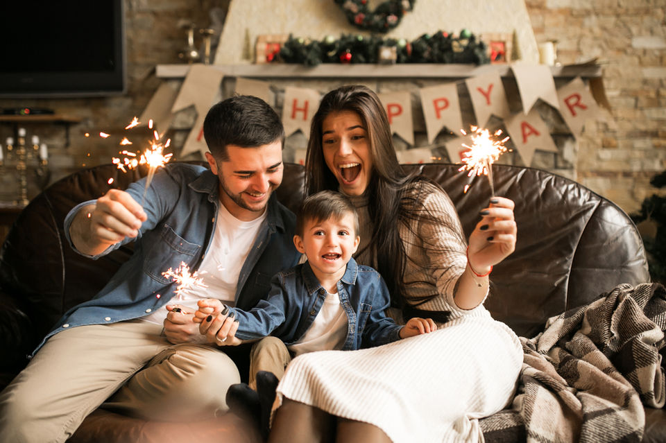 New family celebrating an event with sparklers and a little child