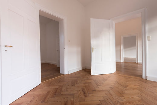 An empty room featuring wooden flooring and plain white walls