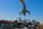 Large crane cars over a pile of scrap cars