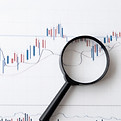 Financial forecast graphs and a magnifying glass.