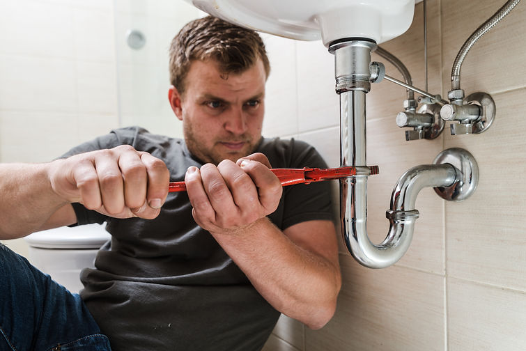 A plumber at work fixing a sink pipe