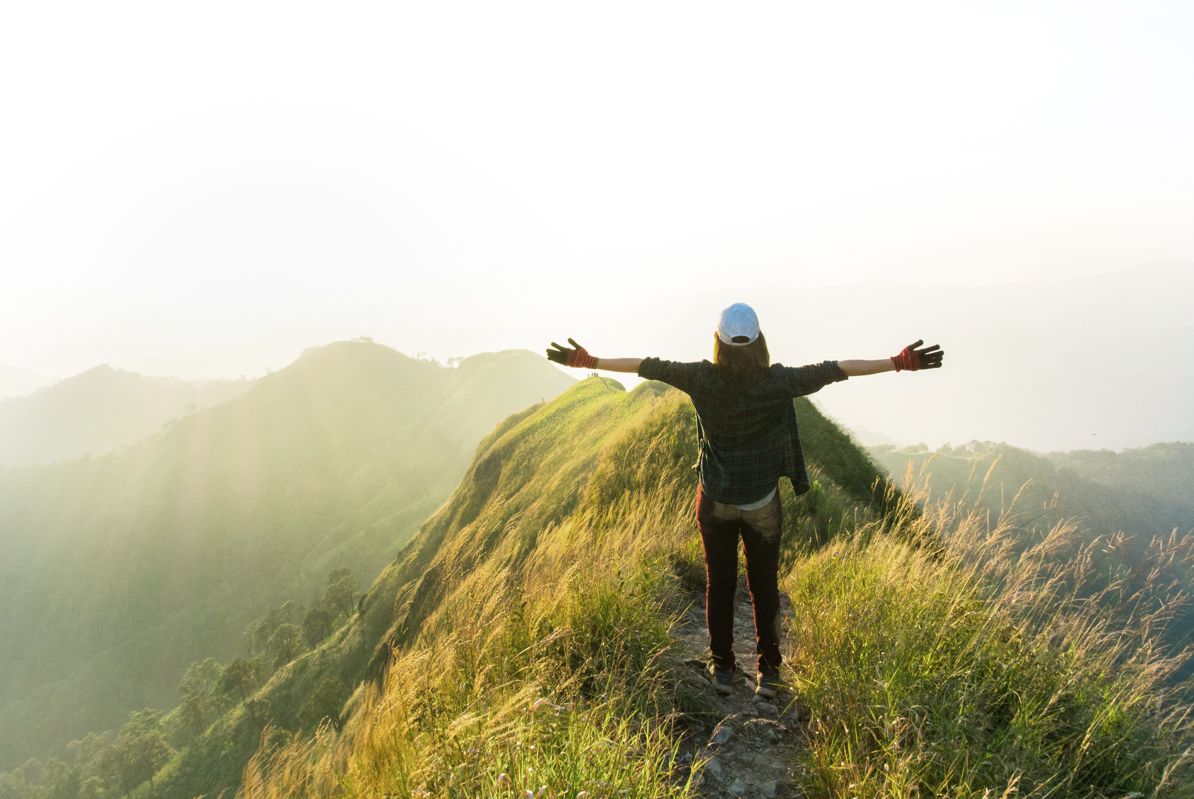 person standing on a ridge with their arms spread open wide