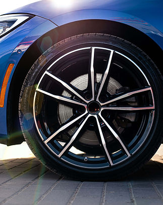 A close-up of a sleek car wheel with a glossy, multi-spoke rim design.