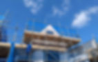 A house under construction with scaffolding and blue netting