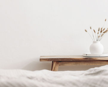 Belle table console en bois massif sur le côté d'un lit avec une petite décoration fleurie.