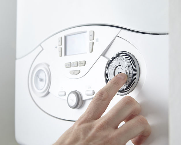 close-up image of a person's hand while adjusting boiler temperature
