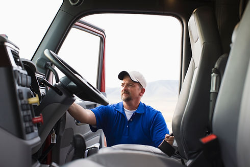 Man sits in a vehicle, reaching for the steering wheel