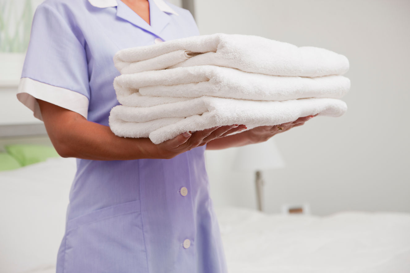 Maid carrying towels in hotel room