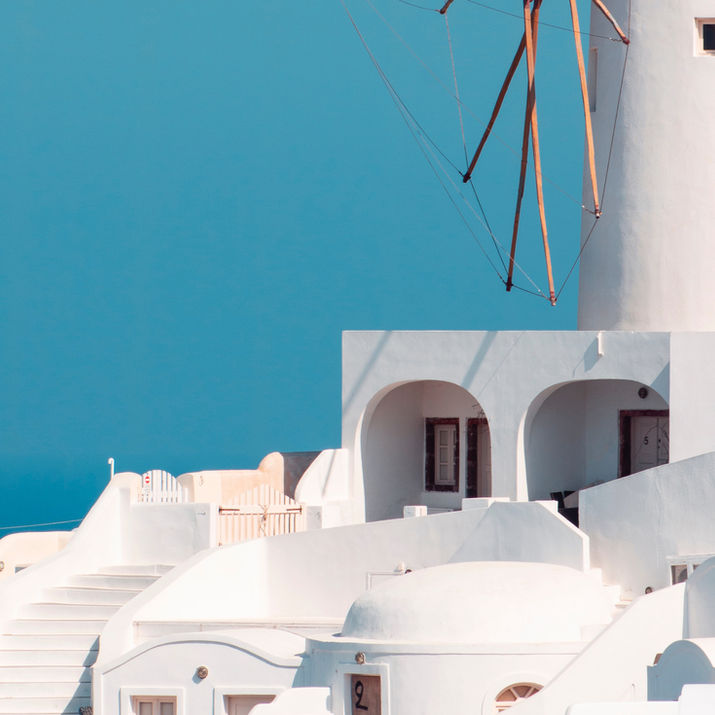 White architecture of Santorini, Greece, with a windmill against a blue sky.