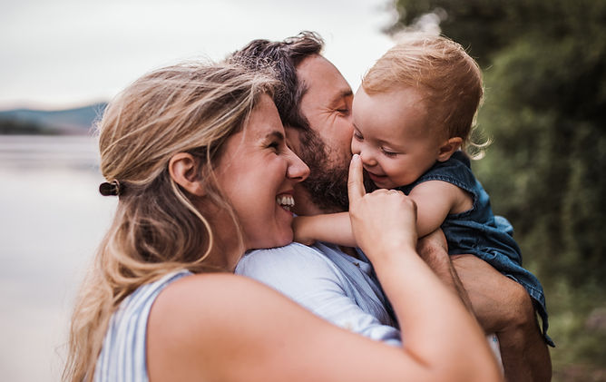 Loving parents hugging their toddler, symbolizing the importance of trust and family alignment in our nanny placement process.