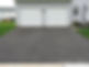 asphalt driveway leading to a garage with two white doors