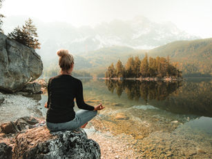 Girl meditating overlooking a peaceful river surrounded by nature