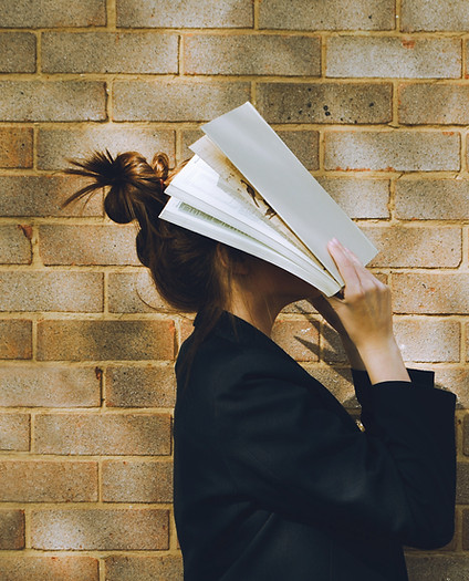 Frau hält ein Buch vor dem Gesicht
