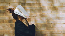 mulher apoiando um livro no rosto