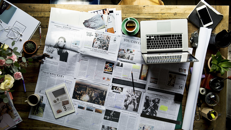 Desk with newspaper, tea, computer, phone, and flowers on it