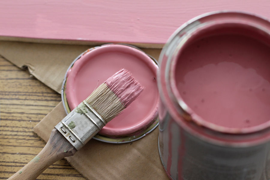 Pink paint can with brush on pink background