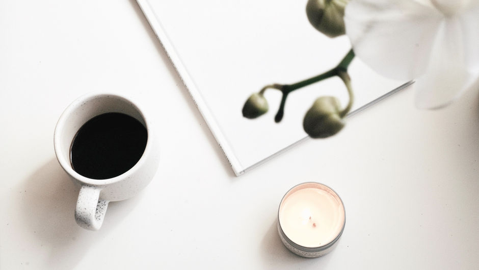 Coffee cup and open notebook on a table in natural light